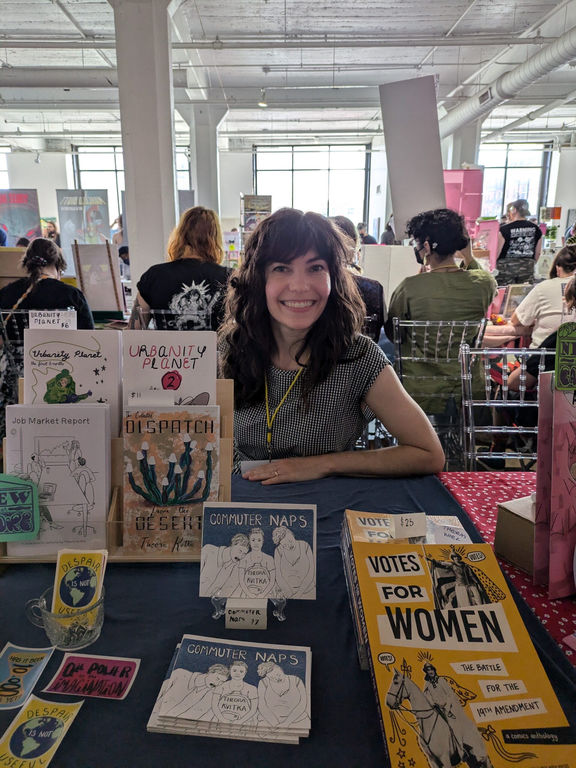 Photograph of Theora sitting at her booth at CAKE Chicago 2024.